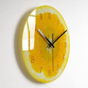 Horloge avec une image de coupe de citron jaune dont on voit la pulpe , installée sur un mur blanc