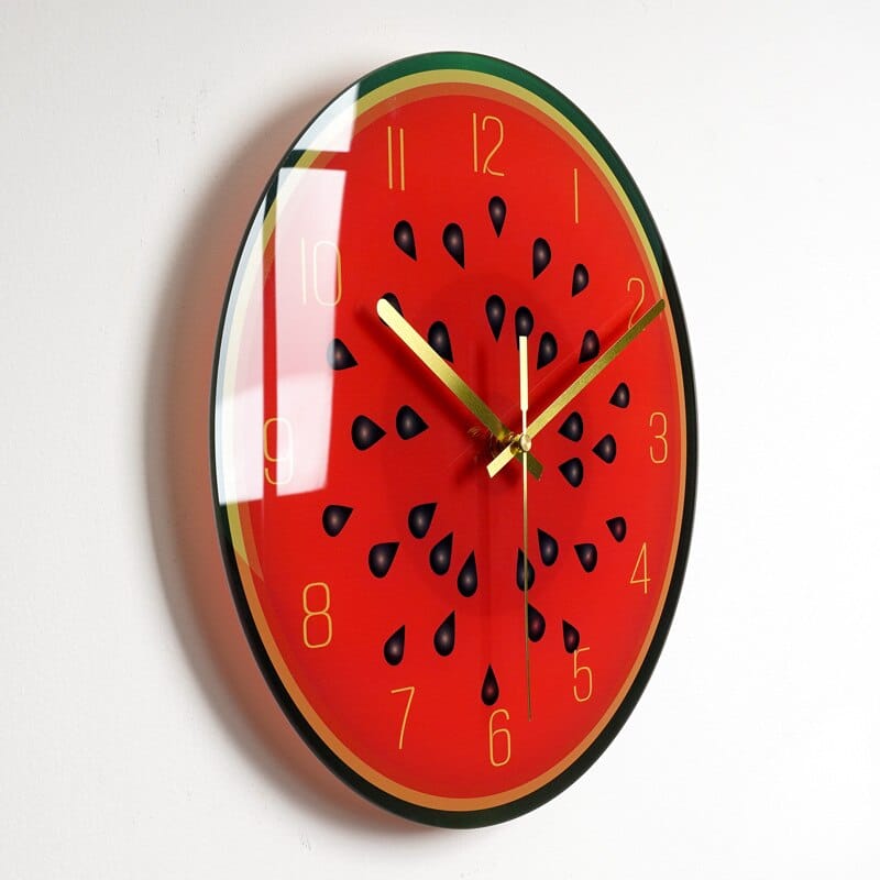 Horloge avec une image de coupe de pastèque dont on voit la pulpe , installée sur un mur blanc