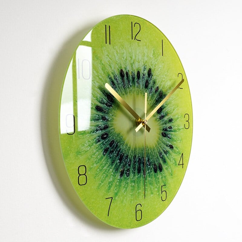 Horloge avec une image de coupe de kiwi dont on voit la pulpe , installée sur un mur blanc