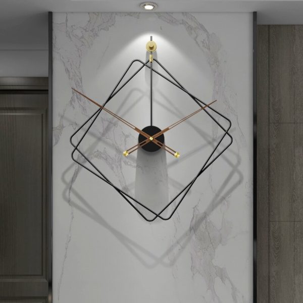 Horloge en forme de losange en métal design est installée sur un mur blan et éclairée par le haut
