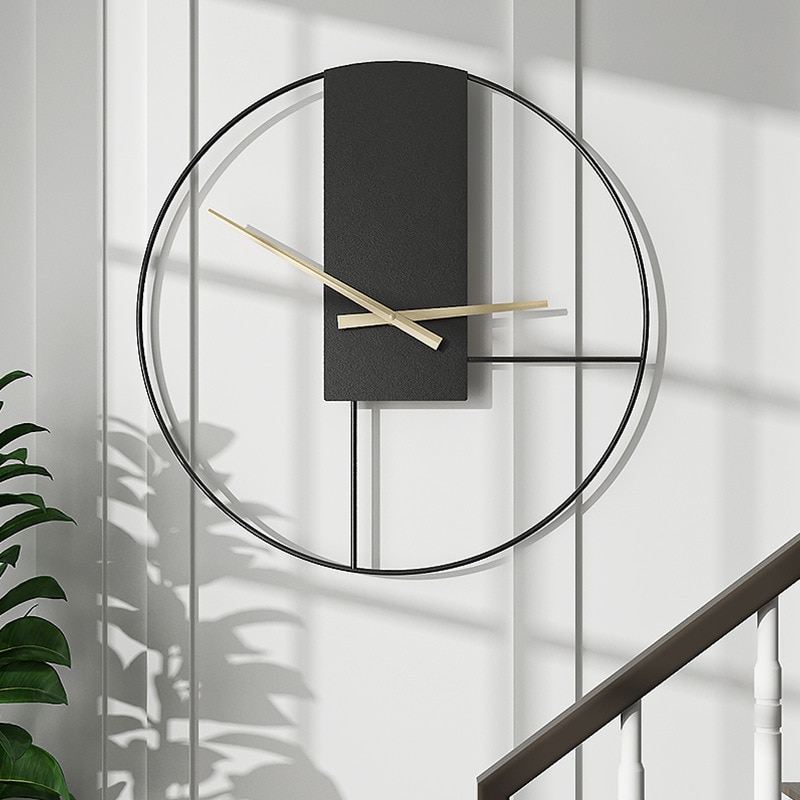 Sur un mur blanc , en guise de décoration dans un escalier dont la rambarde est en bois, horloge en métal minimaliste style scandinave noire