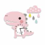 Horloge murale pour enfant en forme de petit dinosaure rose , avec les petites pointes sur le dos grises, le cadran avec aiguilles au niveau du ventre et en haut à droite de la tête un petit nuage rose avec des gouttes de couleurs qui en tombent