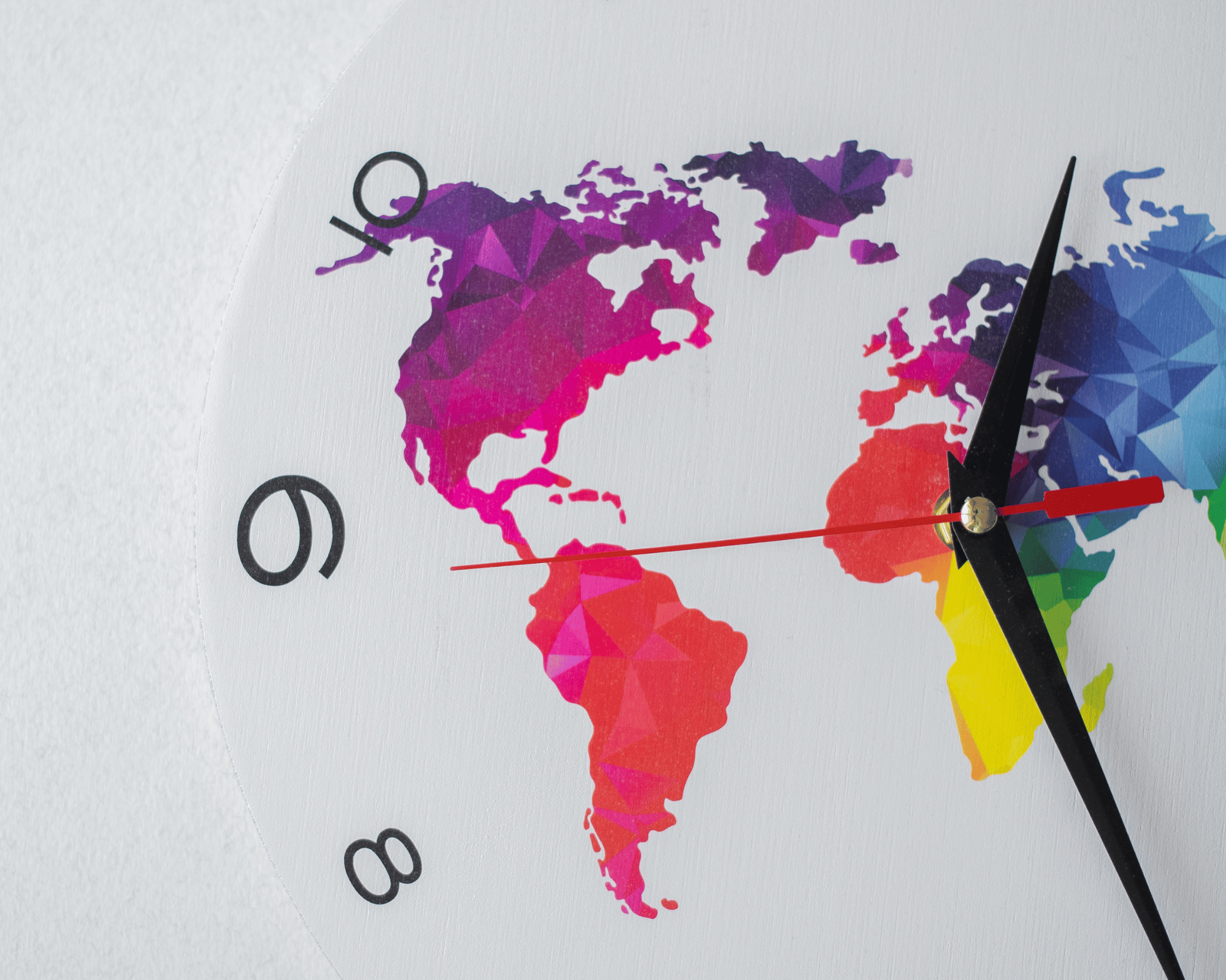 partie d'horloge blanche dont on voit les chiffres du côté du chiffre 9 et sur son cadran il y a une partie de la map monde colorée en multicolore