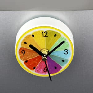 Horloge murale petite et pratique avec design d'agrume coupé en deux et colorié en multicolore posé sur un support gris de cuisine