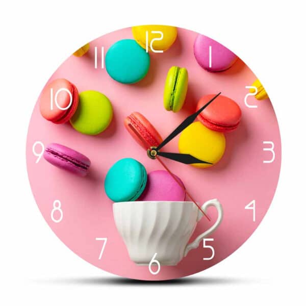 Horloge murale en acrylique avec motif de macarons sur fond rose présentée sur fond blanc
