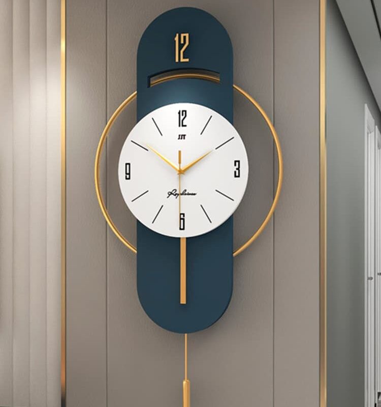 Grande horloge murale au design nordique en métal, de couleur bleu et or avec un cadran blanc nordique et 3 aiguilles, positionné sur un plateau ovale bleu et des armatures couleur or qui l'entoure