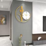 Horloge murale design avec forme de 3 brins de blé de couleur or collé à et un cadran nordique blanc avec ses 3 aiguilles, située dans une pièce à vivre