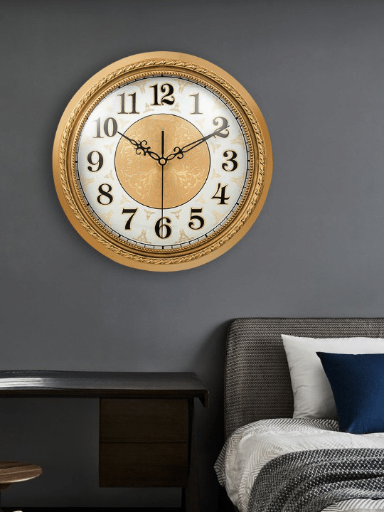Horloge murale or silencieuse artistique dorée présenté sur un mur au dessus d'un lit