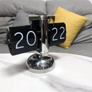 Horloge sur Pied Style Vintage Géométrique posée sur une table blanche avec un canapé et des coussins derrière