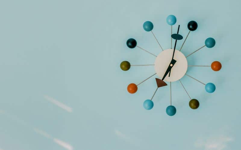horloge murale design avec des boules coloré et des aiguilles en flèche