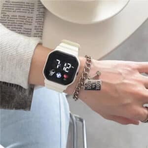 Montre Digitale Femme Légère avec Écran LED sur le poignet d'une femme avec un bracelet au-dessus d'un magazine et d'une table