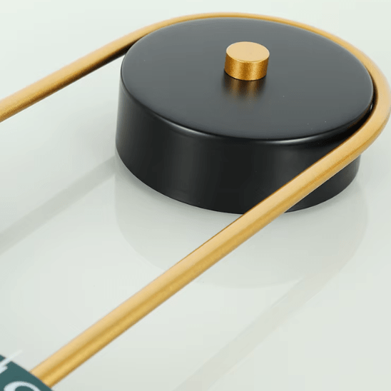 horloge design murale decorative en metal dore zoom sur un rond noir et tiges dorées