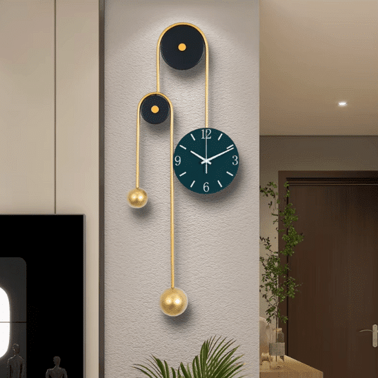 horloge design murale decorative en metal dore sur un mur central. On voit un cadre noir à gauche et une plante verte en bas de l'horloge