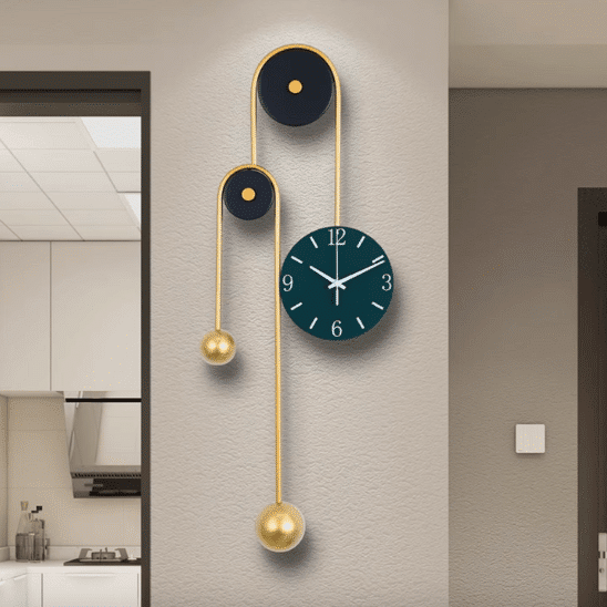 horloge design murale decorative en metal dore sur un mur central. On voit un bouton blanc à droite près d'une porte; l'horloge est sur fond beige